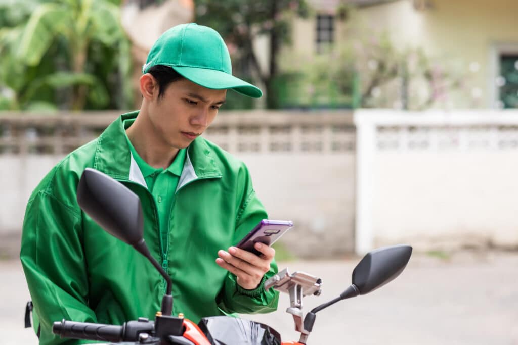 motoboy sentado na moto olhando preocupado para o celular