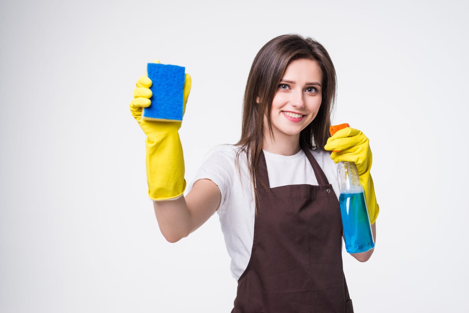 jovem empregada doméstica com luva amarela segurando esponja e borrifador